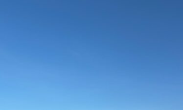A camel caravan with handler under a vibrant blue sky in Marrakech desert.