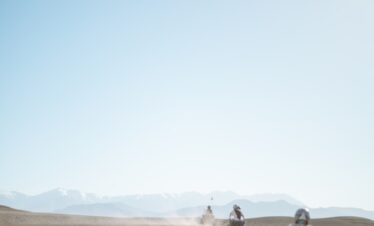 people riding camel on desert during daytime