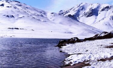 snow covered mountain near body of water during daytime