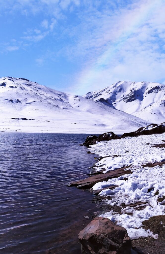 snow covered mountain near body of water during daytime