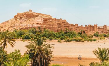 people walking on brown sand near brown rock formation during daytime