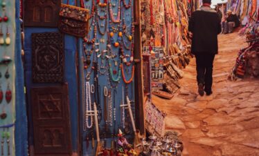 man in black jacket standing in front of blue and white painted wall